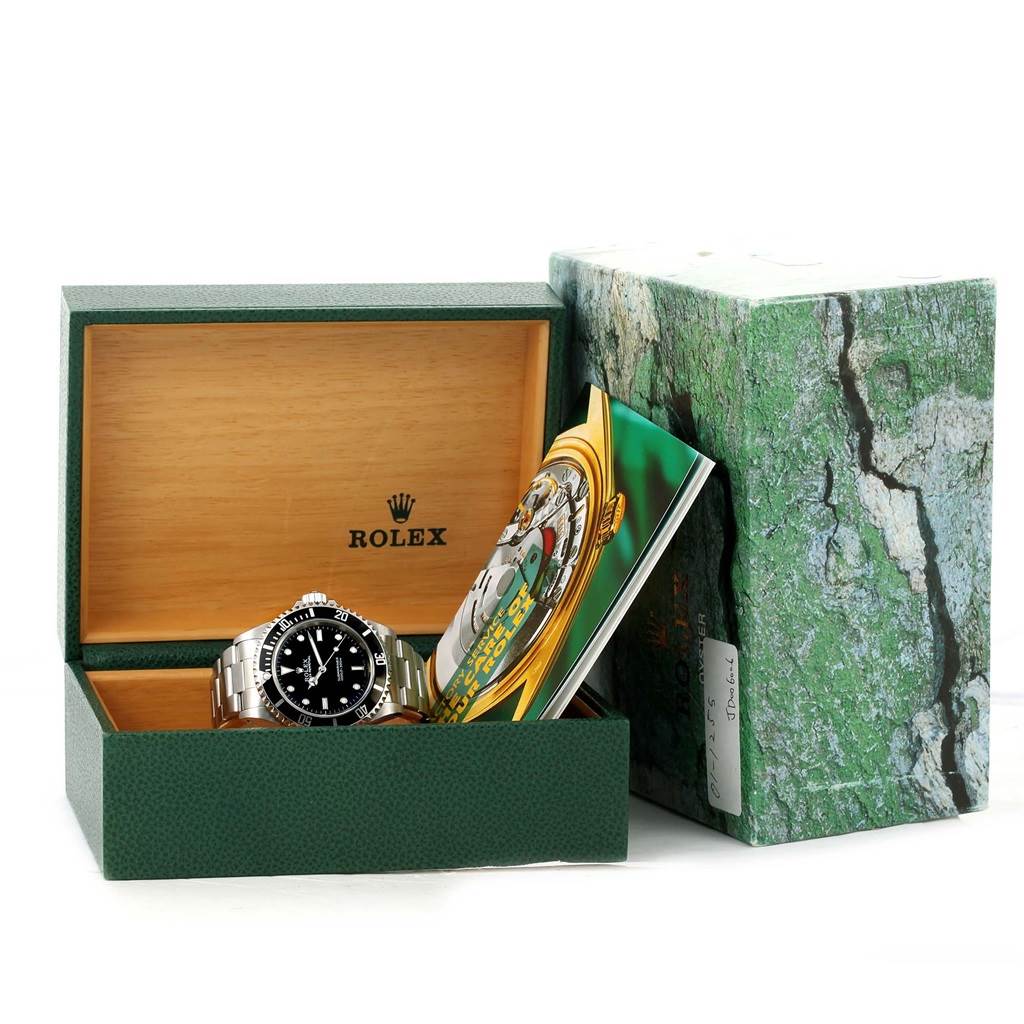 The Rolex Submariner 14060 Men
s Stainless Steel Black Dial 14060 Men
s Stainless Steel Black Dial watch is displayed front-on inside an open green box, with its booklet and outer packaging visible.