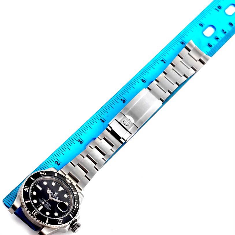 The image shows a top view of a Rolex Submariner 116610 Men
s Stainless Steel Black Dial 116610 Men
s Stainless Steel Black Dial watch with its stainless steel bracelet next to a blue ruler.