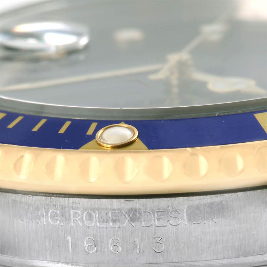 This close-up image of the Rolex Submariner 16613 Men's Steel and Gold (two tone) Blue Dial 16613 Men's Steel and Gold (two tone) Blue Dial shows part of the bezel, crystal, and engraved case.
