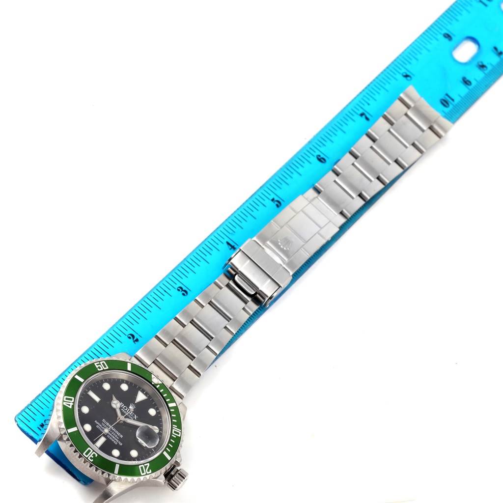 The Rolex Submariner 16610LV Men
s Stainless Steel Black Dial 16610LV Men
s Stainless Steel Black Dial watch is displayed flat with its bracelet extended and a blue ruler aligned along its length.