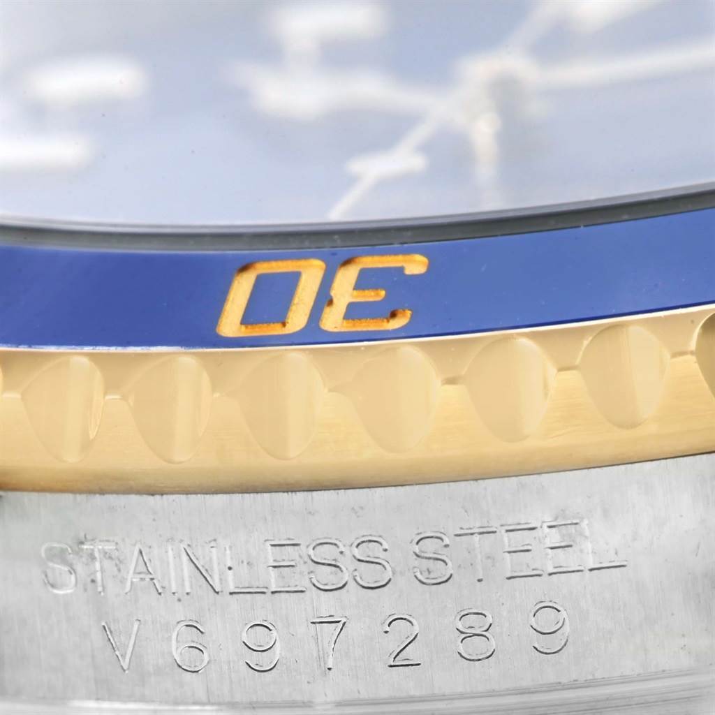 This close-up image shows the bezel and part of the case of a Rolex Submariner 116613 Men
s Steel and Gold (two tone) Blue Dial 116613 Men
s Steel and Gold (two tone) Blue Dial, highlighting the "STAINLESS STEEL" engraving and partial serial number.