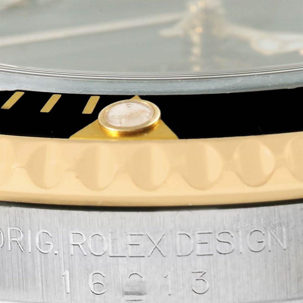 Close-up of the bezel and case side of a Rolex Submariner 16613 Men's Steel and Gold (two tone) Black Dial 16613 Men's Steel and Gold (two tone) Black Dial, featuring the model's markings and part of the bezel insert.