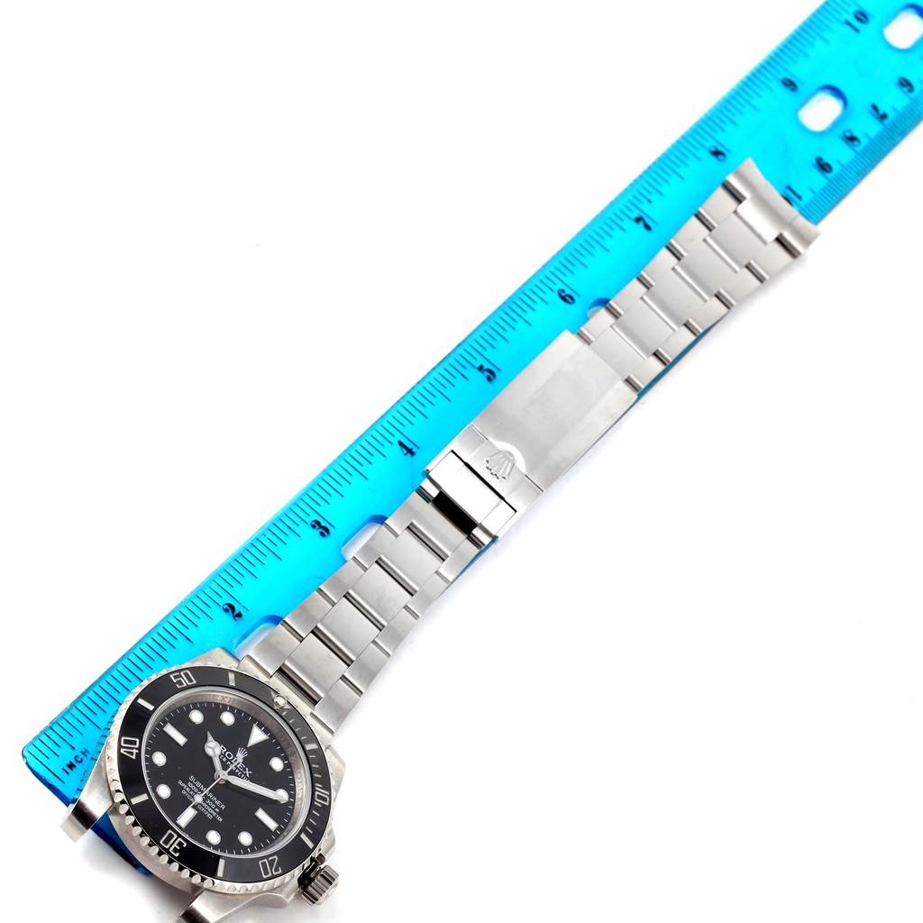 The image shows a Rolex Submariner 114060 Men
s Stainless Steel Black Dial 114060 Men
s Stainless Steel Black Dial watch, including the watch case, bezel, dial, and bracelet, laid flat next to a ruler.
