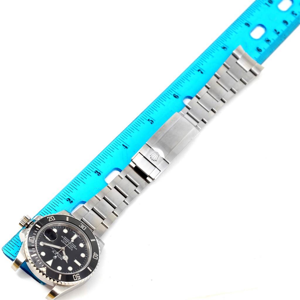 The image shows a Rolex Submariner 116610 Men's Stainless Steel Black Dial 116610 Men's Stainless Steel Black Dial watch laid flat next to a ruler, displaying its face, bezel, and bracelet.