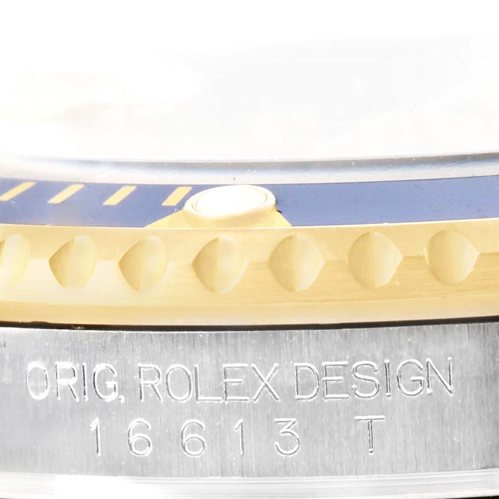 This close-up image of the Rolex Submariner 16613 Men's Steel and Gold (two tone) Champagne Dial 16613 Men's Steel and Gold (two tone) Champagne Dial model showcases the bezel and part of the caseback with engraved model information.