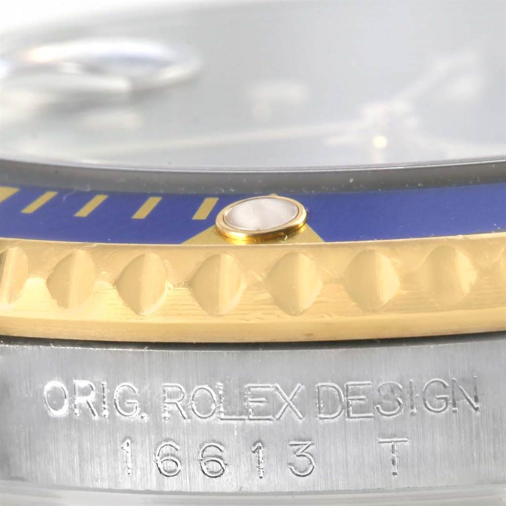 A close-up of the Rolex Submariner 16613 Men's Steel and Gold (two tone) Blue Dial 16613 Men's Steel and Gold (two tone) Blue Dial highlights the bezel, a pearl marker, and the inscribed case with model number 16613T.