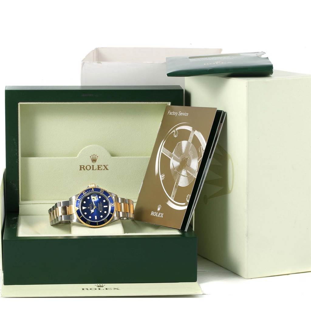 The image shows a Rolex Submariner 16613 Men's Steel and Gold (two tone) Blue Dial 16613 Men's Steel and Gold (two tone) Blue Dial watch in its box with accompanying manuals placed at an angle.