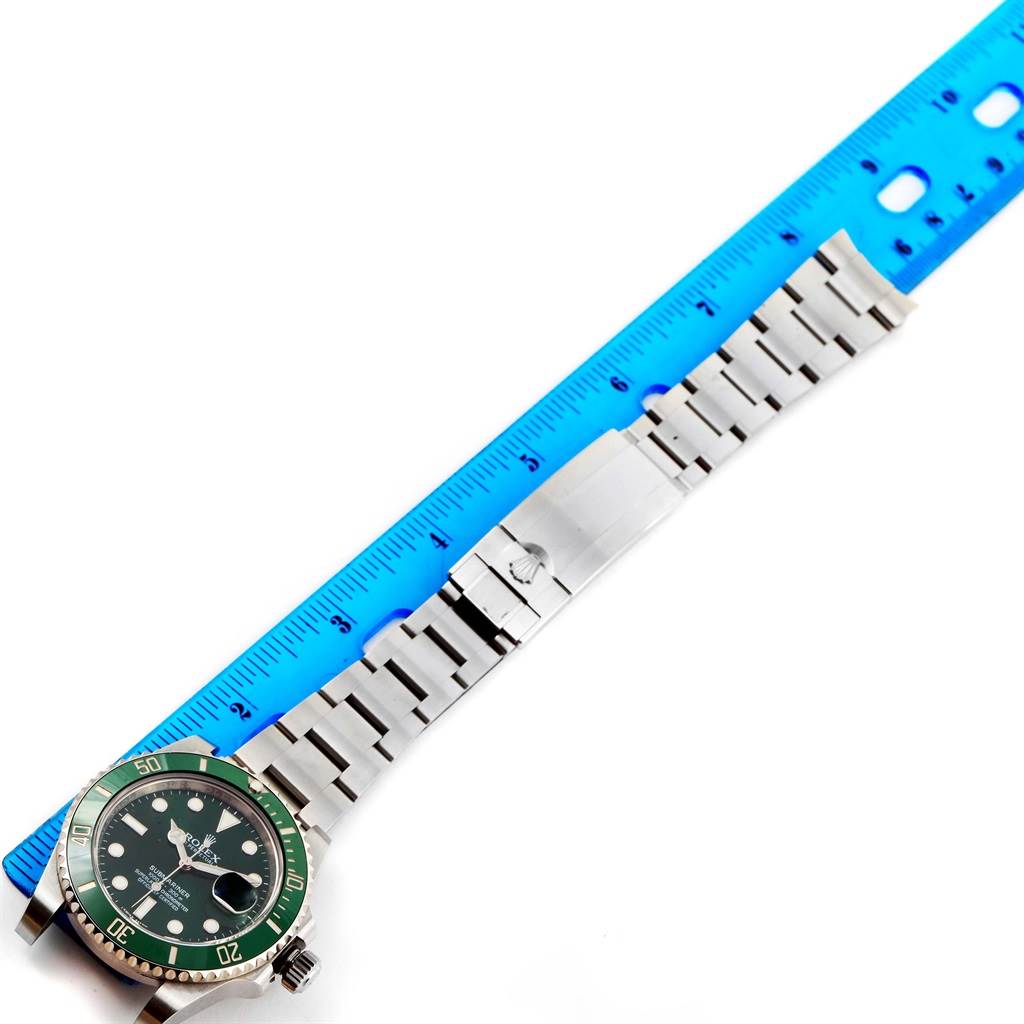 The image shows the Rolex Submariner 116610LV Men's Stainless Steel Green Dial 116610LV Men's Stainless Steel Green Dial watch lying flat next to a blue ruler, highlighting its stainless steel bracelet and green bezel.