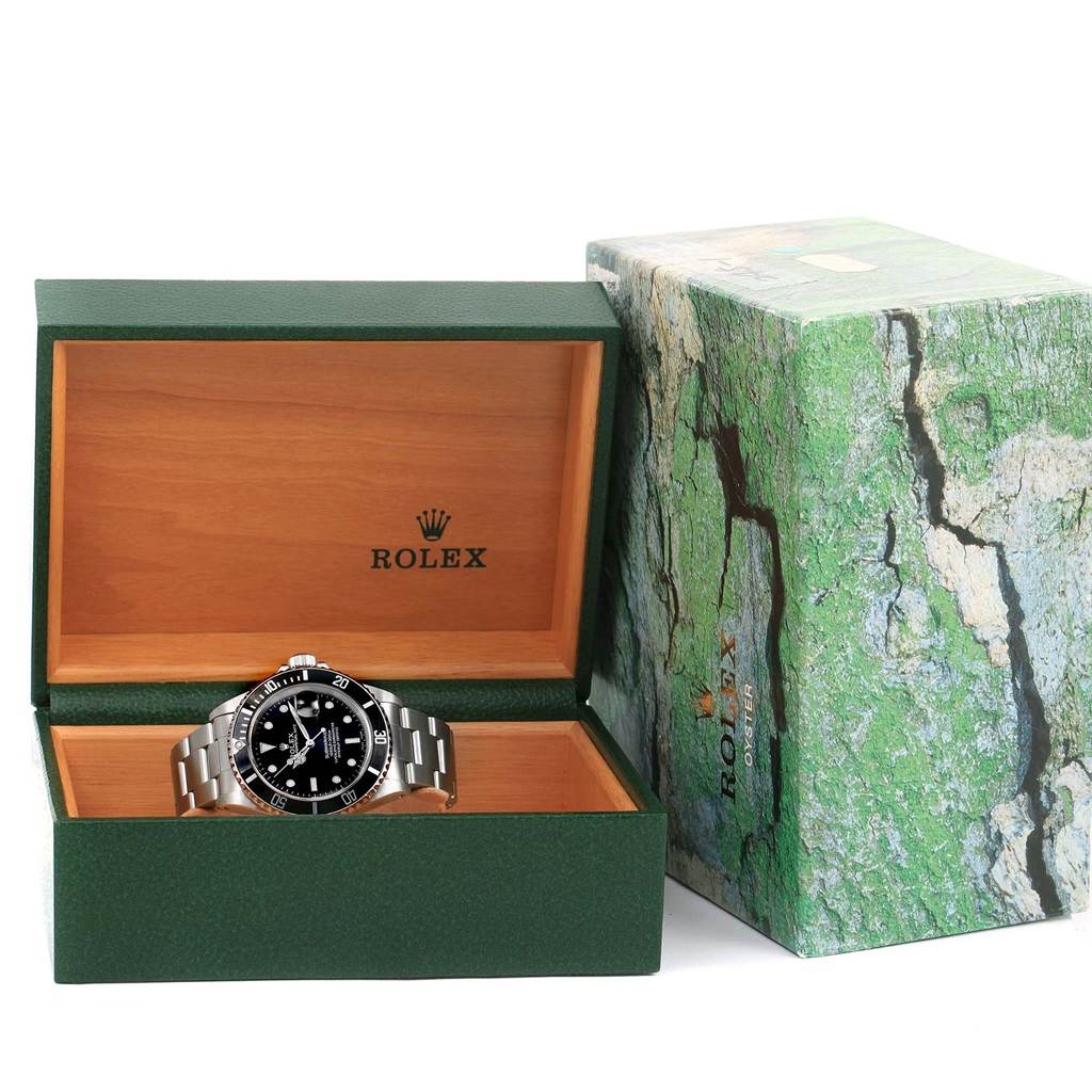 The Rolex Submariner 16610 Men's Stainless Steel Black Dial 16610 Men's Stainless Steel Black Dial watch is shown in its open green and wood-tone box, along with the branded outer box.