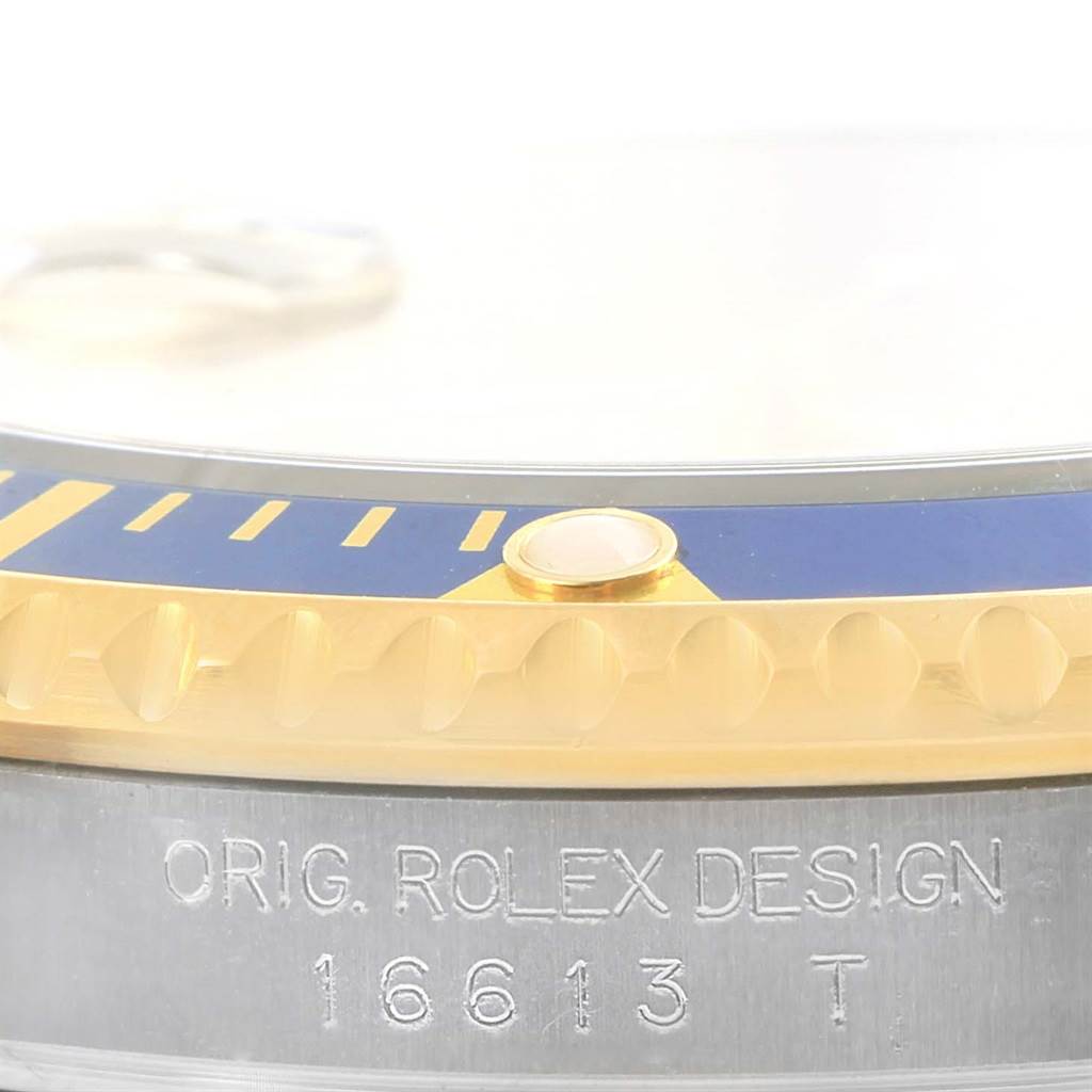 This image shows a close-up of the bezel, case, and engraved model number of the Rolex Submariner 16613 Men's Steel and Gold (two tone) Champagne Dial 16613 Men's Steel and Gold (two tone) Champagne Dial.