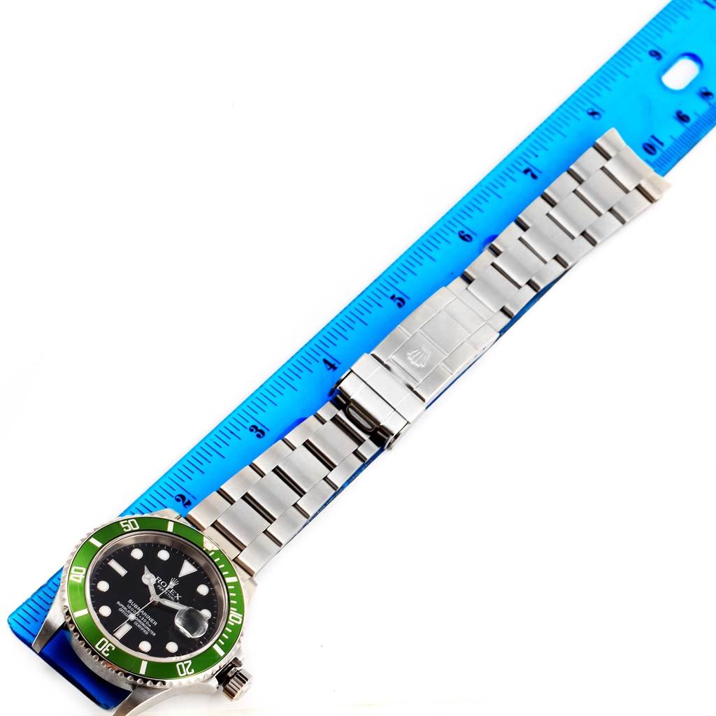 The image shows a Rolex Submariner 16610LV Men's Stainless Steel Black Dial 16610LV Men's Stainless Steel Black Dial watch laid flat next to a blue ruler, displaying its face, bezel, and metal bracelet.