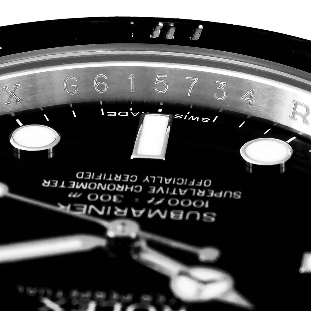 This close-up image of a Rolex Submariner 114060 Men's Stainless Steel Black Dial 114060 Men's Stainless Steel Black Dial watch focuses on part of the dial, text, and the rehaut with an engraved serial number.