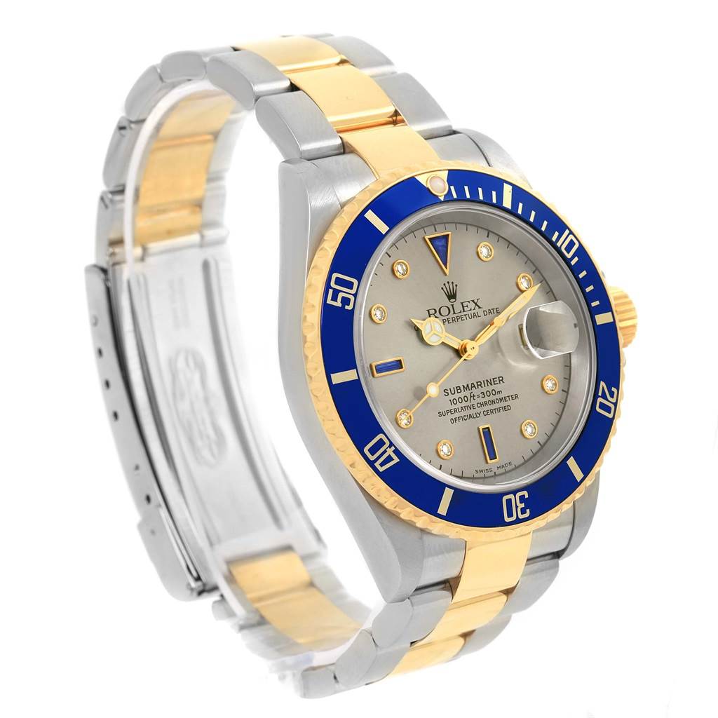 The Rolex Submariner 16613 Men's Steel and Gold (two tone) Grey Dial 16613 Men's Steel and Gold (two tone) Grey Dial watch is shown at an oblique angle, displaying the face, bezel, crown, and part of the bracelet.