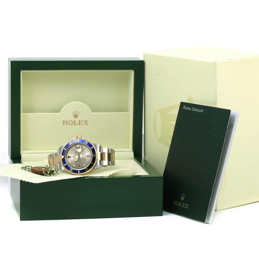 The image shows a Rolex Submariner 16613 Men's Steel and Gold (two tone) Grey Dial 16613 Men's Steel and Gold (two tone) Grey Dial watch in its open box, along with a booklet and tag, viewed from the front.