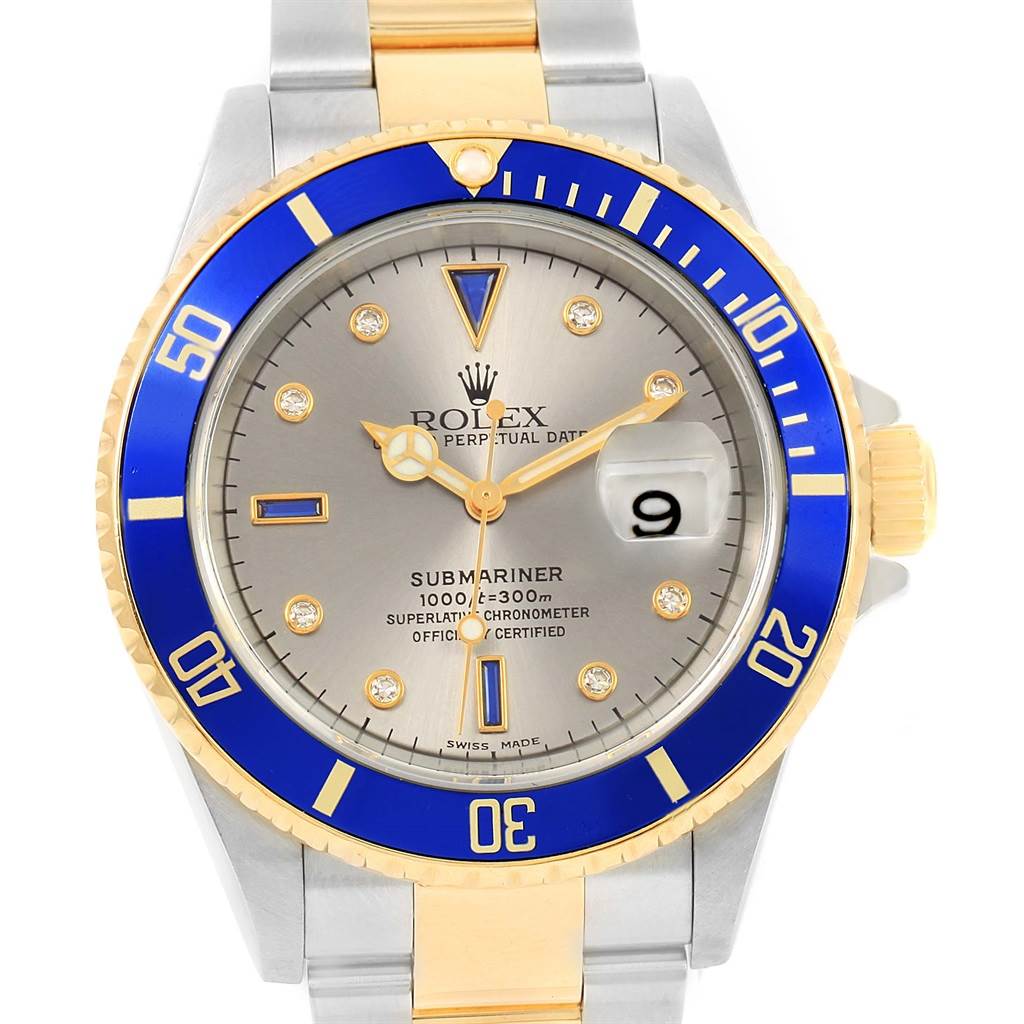 The image shows a frontal view of a Rolex Submariner 16613 Men's Steel and Gold (two tone) Grey Dial 16613 Men's Steel and Gold (two tone) Grey Dial watch, highlighting its blue bezel, grey dial, and two-tone bracelet.