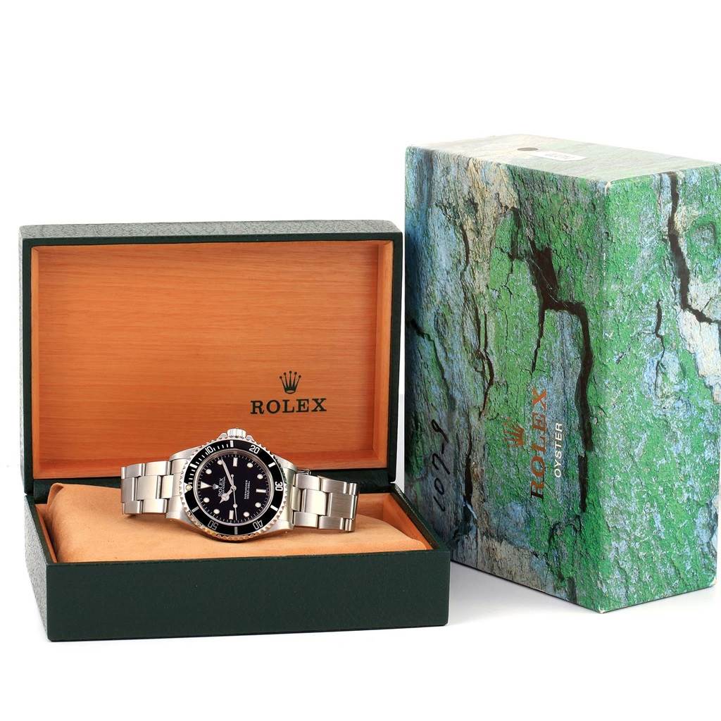 The Rolex Submariner 14060 Men's Stainless Steel Black Dial 14060 Men's Stainless Steel Black Dial watch is displayed in an open box, showing the face and bracelet, with the outer green case beside it.