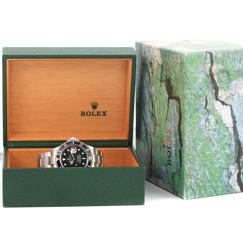 The Rolex Submariner 16610 Men's Stainless Steel Black Dial 16610 Men's Stainless Steel Black Dial watch is displayed front-on in an open green box with the outer packaging beside it.