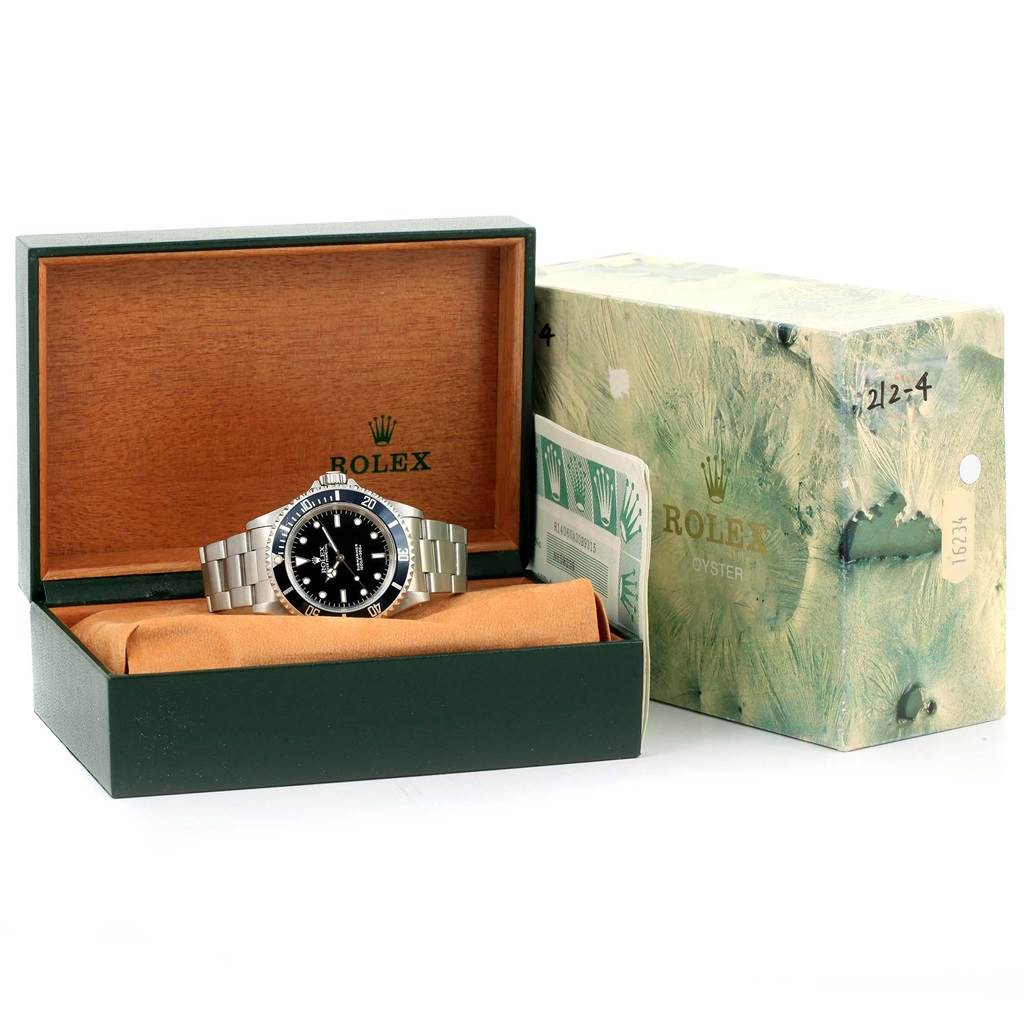 This Rolex Submariner 14060 Men's Stainless Steel Black Dial 14060 Men's Stainless Steel Black Dial watch is shown at a slight angle inside its green and wooden box, with the outer box and papers visible.