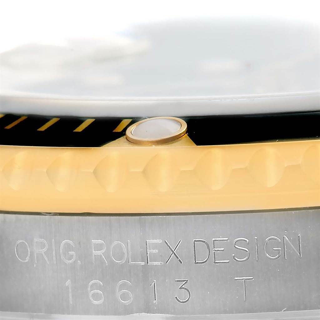 The image shows a close-up of the bezel, illuminous pip, and part of the case with the engraved model number of the Rolex Submariner 16613 Men's Steel and Gold (two tone) Black Dial 16613 Men's Steel and Gold (two tone) Black Dial.