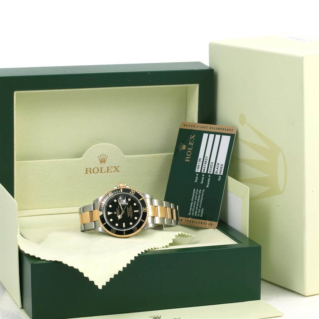 The image shows a Rolex Submariner 16613 Men's Steel and Gold (two tone) Black Dial 16613 Men's Steel and Gold (two tone) Black Dial watch, displayed in its open box, alongside its certification card.