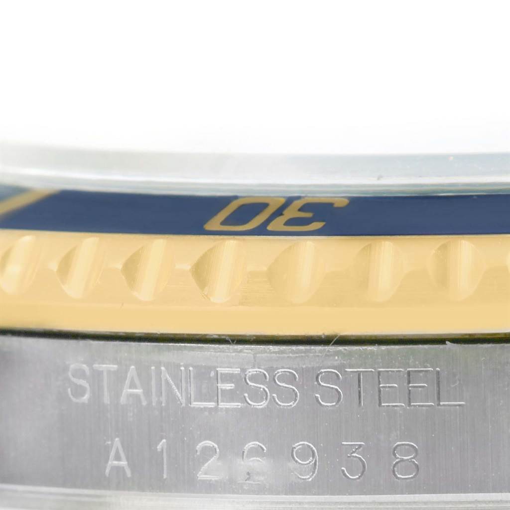 The image shows a close-up angle of the bezel and case of a Rolex Submariner 16613 Men's Steel and Gold (two tone) Champagne Dial 16613 Men's Steel and Gold (two tone) Champagne Dial watch, highlighting part of the minute marker and the stainless steel engraved text.