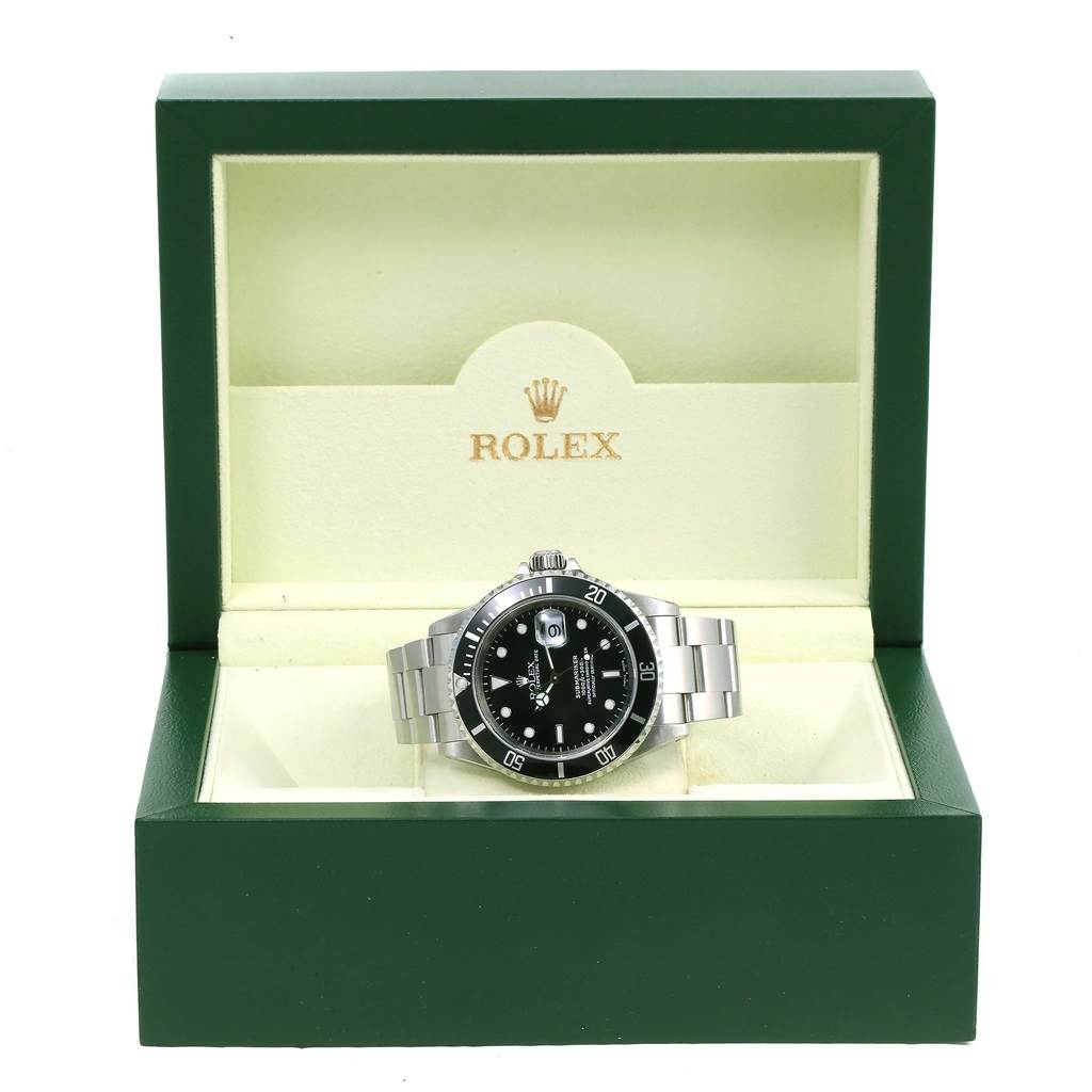 This image shows a Rolex Submariner 16610 Men's Stainless Steel Black Dial 16610 Men's Stainless Steel Black Dial watch on display inside its open, green, branded box from a front angle.