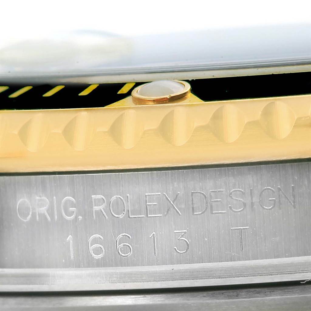This close-up image shows the side of the bezel and case of a Rolex Submariner 16613 Men's Steel and Gold (two tone) Black Dial 16613 Men's Steel and Gold (two tone) Black Dial, including the model number engraving.