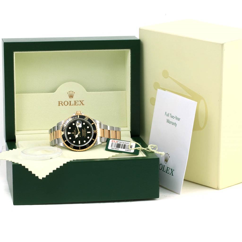 The Rolex Submariner 16613 Men's Steel and Gold (two tone) Black Dial 16613 Men's Steel and Gold (two tone) Black Dial watch is displayed inside its open box, alongside a warranty card and tags.