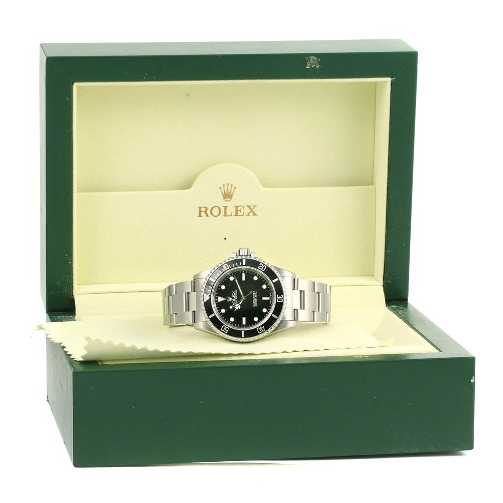 The watch, a Rolex Submariner 14060 Men's Stainless Steel Black Dial 14060 Men's Stainless Steel Black Dial, is pictured front-on inside its open green and cream case.