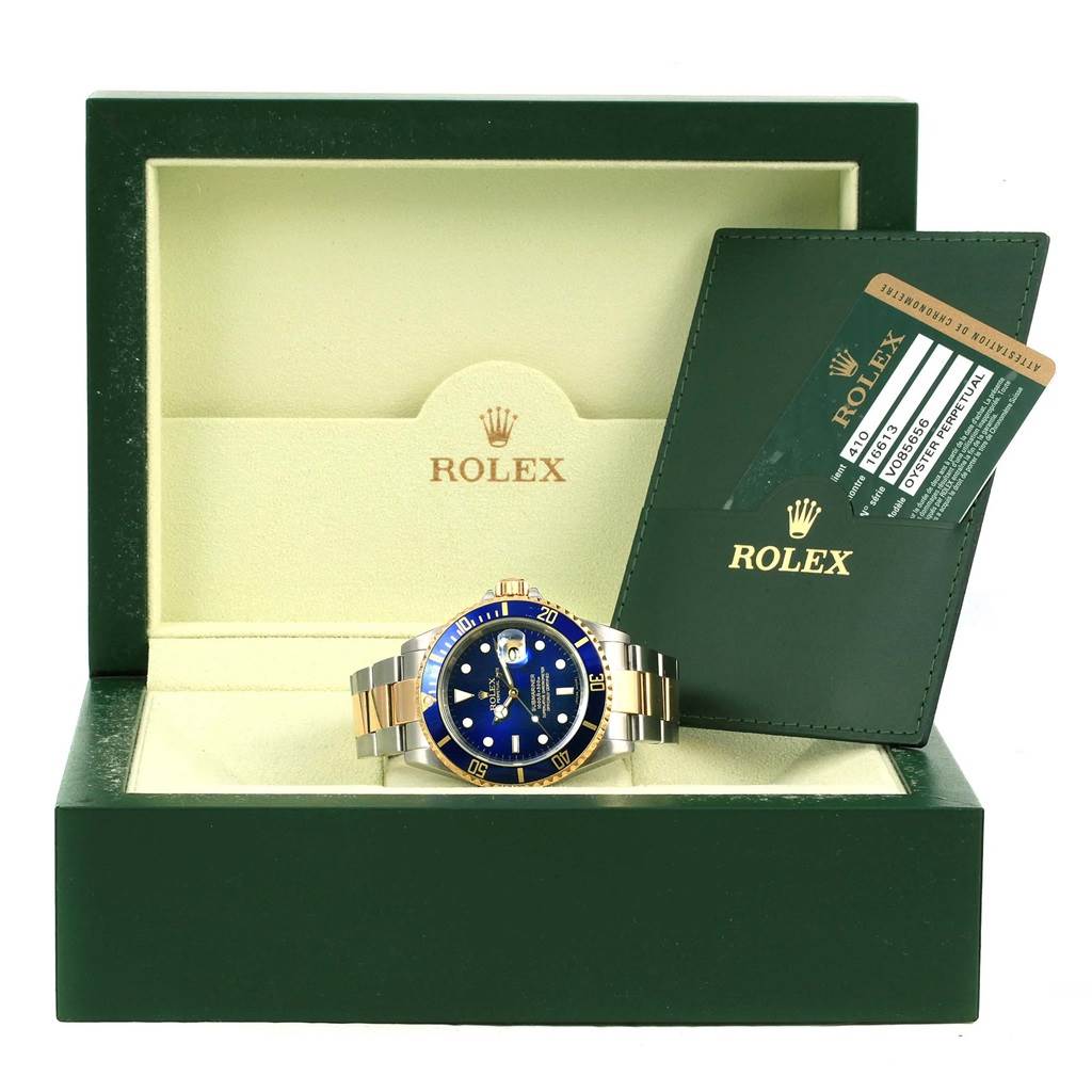 The image shows a front view of a Rolex Submariner 16613 Men
s Steel and Gold (two tone) Blue Dial 16613 Men
s Steel and Gold (two tone) Blue Dial watch in its open box, alongside warranty cards.