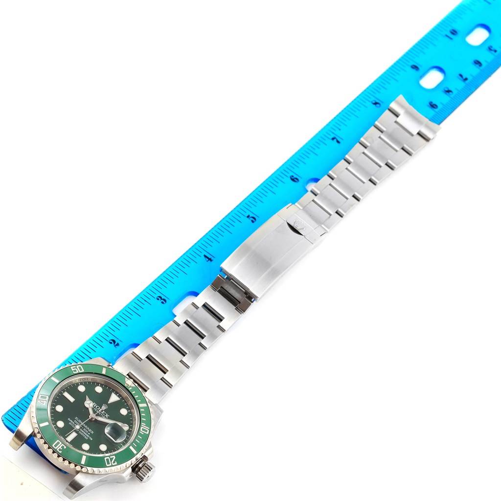 This image shows a Rolex Submariner 116610LV Men
s Stainless Steel Green Dial 116610LV Men
s Stainless Steel Green Dial watch with a green bezel and face, along with its stainless steel bracelet and clasp measured against a ruler.