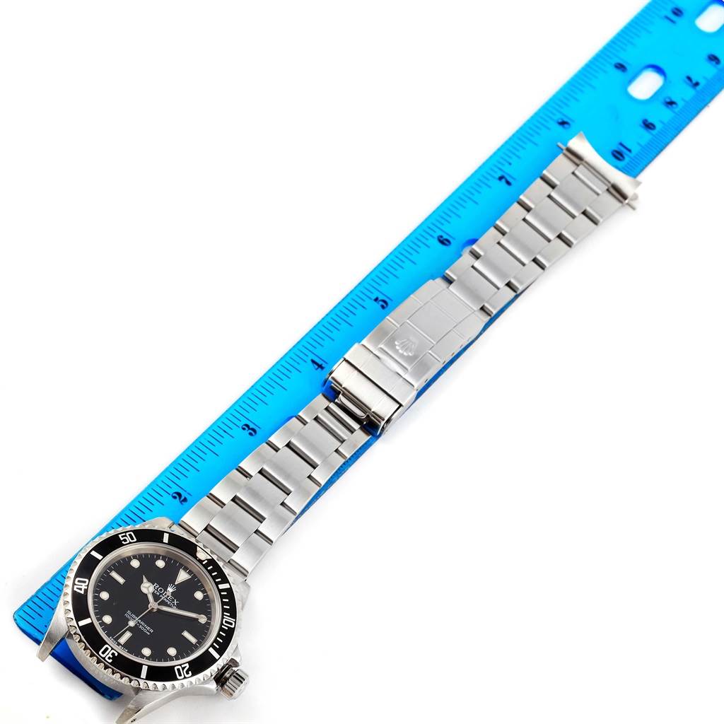 The image shows a Rolex Submariner 14060 Men
s Stainless Steel Black Dial 14060 Men
s Stainless Steel Black Dial watch laid flat with its band extended next to a ruler.