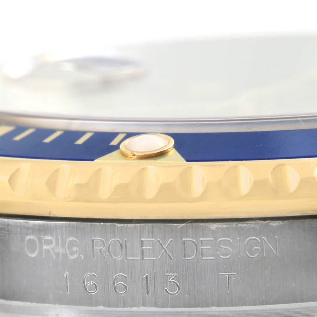 This close-up angle of the Rolex Submariner 16613 Men's Steel and Gold (two tone) Grey Dial 16613 Men's Steel and Gold (two tone) Grey Dial watch shows the bezel, the edge of the crystal, and the engraved case.