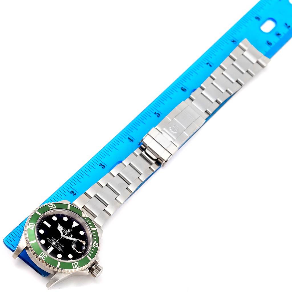 The Rolex Submariner 16610LV Men
s Stainless Steel Black Dial 16610LV Men
s Stainless Steel Black Dial watch is shown laid flat with the full stainless steel band and part of a blue ruler visible.