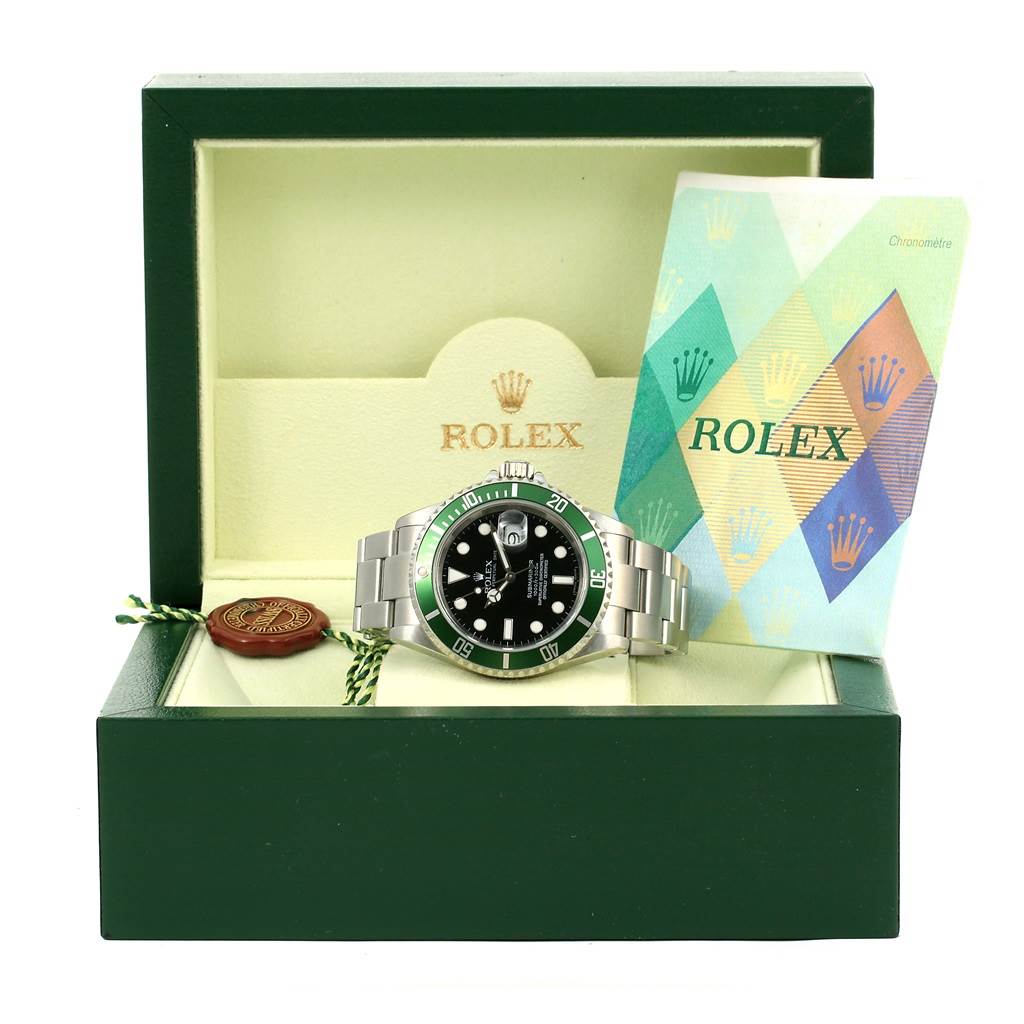 The image shows a front view of a Rolex Submariner 16610LV Men
s Stainless Steel Black Dial 16610LV Men
s Stainless Steel Black Dial watch inside its green box, alongside a booklet and a seal.