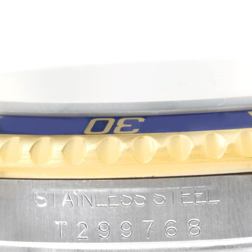 This close-up image of a Rolex Submariner 16613 Men
s Steel and Gold (two tone) Grey Dial 16613 Men
s Steel and Gold (two tone) Grey Dial watch shows its bezel and part of the stainless steel case with engravings.