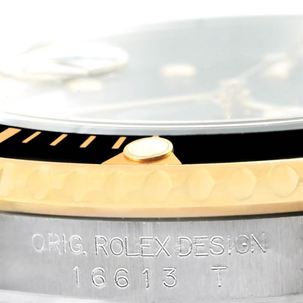 Close-up view of a Rolex Submariner 16613 Men
s Steel and Gold (two tone) Black Dial 16613 Men
s Steel and Gold (two tone) Black Dial showing the bezel, part of the dial, and the case with the model number engraved.