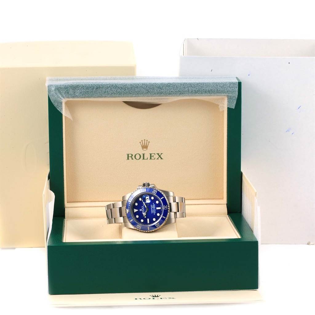 The Rolex Submariner 116619LB Men's White Gold Blue Dial 116619LB Men's White Gold Blue Dial watch is shown from the front, positioned in an opened green and beige Rolex box.