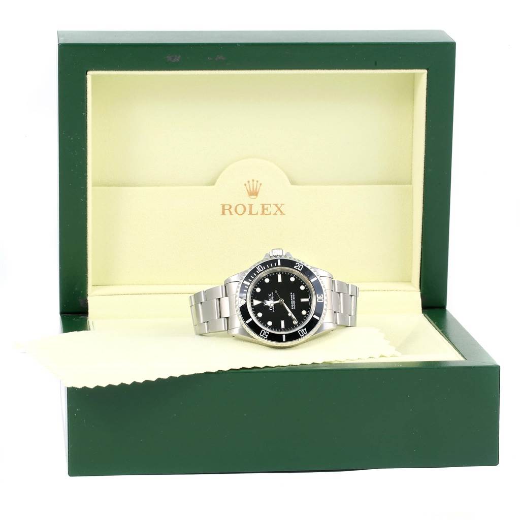 The Rolex Submariner 14060 Men
s Stainless Steel Black Dial 14060 Men
s Stainless Steel Black Dial watch is displayed front-on in an open green and beige box.