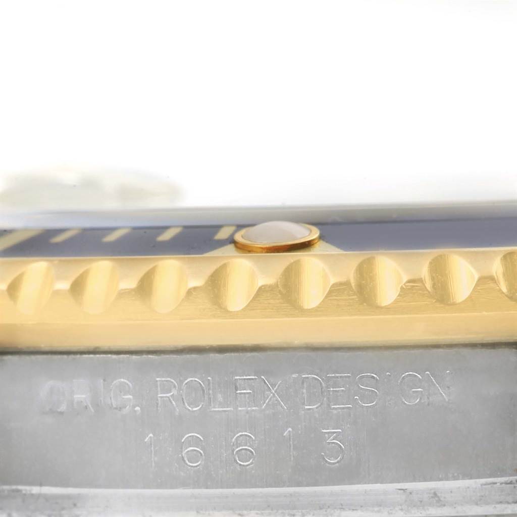 The image shows a close-up side view of a Rolex Submariner 16613 Men
s Steel and Gold (two tone) Blue Dial 16613 Men
s Steel and Gold (two tone) Blue Dial, highlighting its bezel and engraved model number.