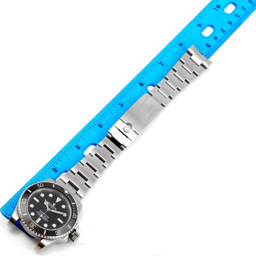 The image shows a Rolex Submariner 114060 Men
s Stainless Steel Black Dial 114060 Men
s Stainless Steel Black Dial watch laid flat with its metal bracelet measured by a blue ruler.
