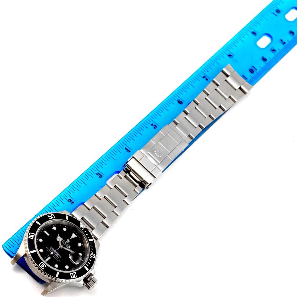 The image shows a side view of a Rolex Submariner 16610 Men's Stainless Steel Black Dial 16610 Men's Stainless Steel Black Dial, highlighting the watch face, bezel, and full bracelet next to a ruler for scale.