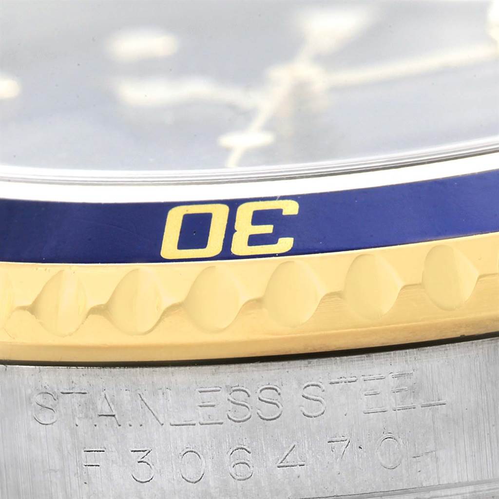 The image shows a close-up of the bezel and edge of the dial along with a part of the engraved case of a Rolex Submariner 16613 Men's Steel and Gold (two tone) Blue Dial 16613 Men's Steel and Gold (two tone) Blue Dial watch.