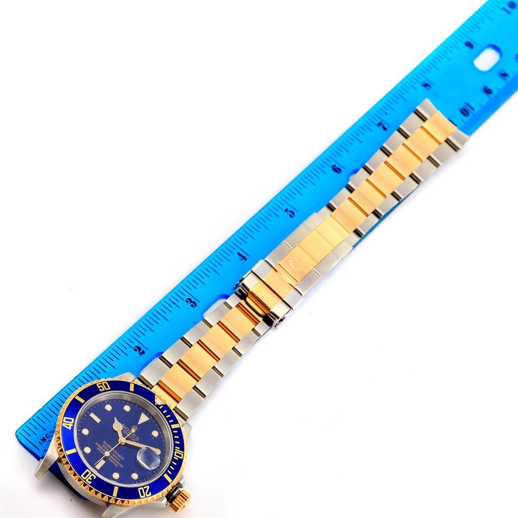 The image shows a top-down view of a Rolex Submariner 16613 Men's Steel and Gold (two tone) Blue Dial 16613 Men's Steel and Gold (two tone) Blue Dial watch, highlighting its blue dial, bezel, and two-tone metal bracelet.