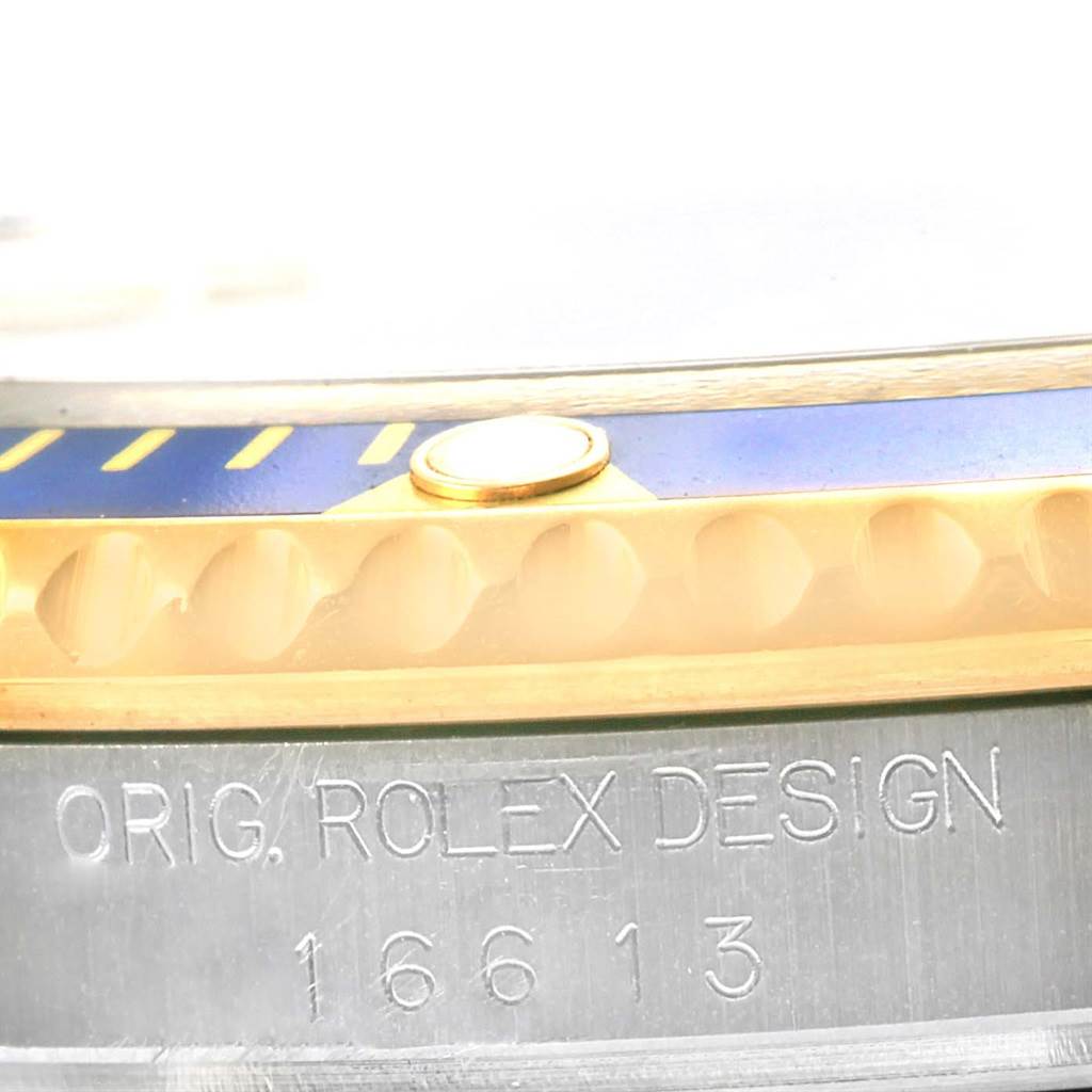 The image shows a close-up of a Rolex Submariner 16613 Men's Steel and Gold (two tone) Blue Dial 16613 Men's Steel and Gold (two tone) Blue Dial watch bezel, case, and engraved model number 16613.