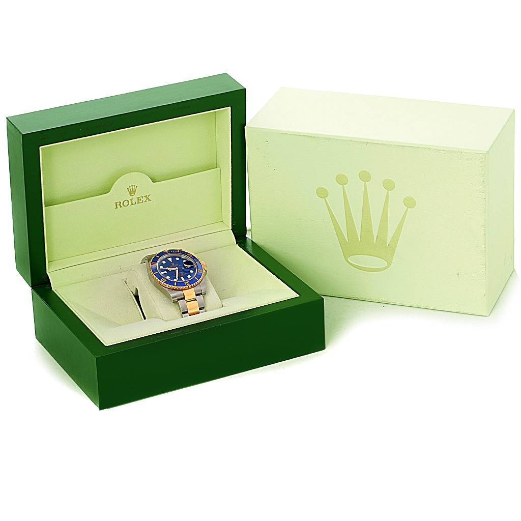 The image shows a Rolex Submariner 116613 Men's Steel and Gold (two tone) Blue Dial 116613 Men's Steel and Gold (two tone) Blue Dial watch inside its green case, displayed alongside the exterior packaging.