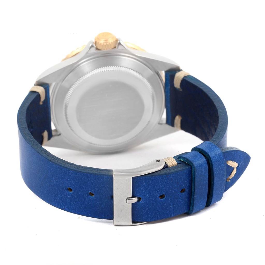 The image shows the back view of a Rolex Submariner 16613 Men
s Steel and Gold (two tone) Blue Dial 16613 Men
s Steel and Gold (two tone) Blue Dial watch case and its blue leather strap with a buckle.