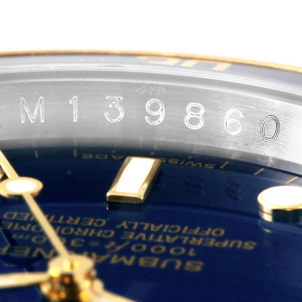 The image shows a close-up of the serial number and part of the dial on a Rolex Submariner 16613 Men
s Steel and Gold (two tone) Blue Dial 16613 Men
s Steel and Gold (two tone) Blue Dial watch.