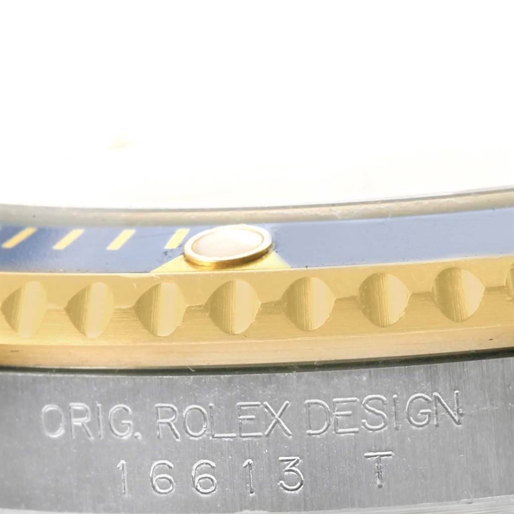 This close-up view of the Rolex Submariner 16613 Men
s Steel and Gold (two tone) Champagne Dial 16613 Men
s Steel and Gold (two tone) Champagne Dial shows the engraved case back and part of the bezel with its notches and pearl marker.