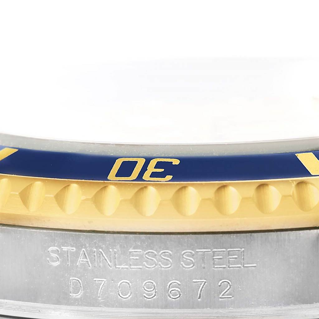 This image shows a close-up of the bezel and part of the case of the Rolex Submariner 16613 Men
s Steel and Gold (two tone) Champagne Dial 16613 Men
s Steel and Gold (two tone) Champagne Dial watch, highlighting the serial number engraving.